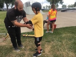 Kyle Johnson helps a skater during a 2017 skate camp.